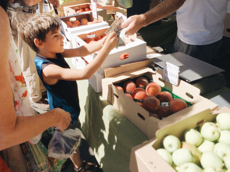 kid buying produce at farmers market
